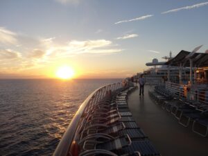 Disney Cruise Line ship at sea during sunset with crew on deck.”